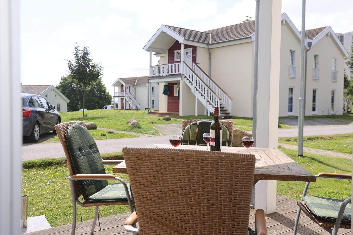 Terrasse mit Tisch und Stühlen. Im Hintergrund stehen mehrstöckige Häuser.