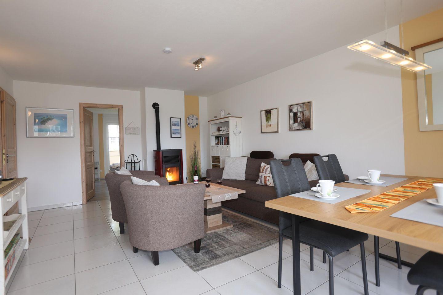 Wohn- und Essbereich mit Kamin, Tisch und Stühlen sowie Sofa und Sessel.