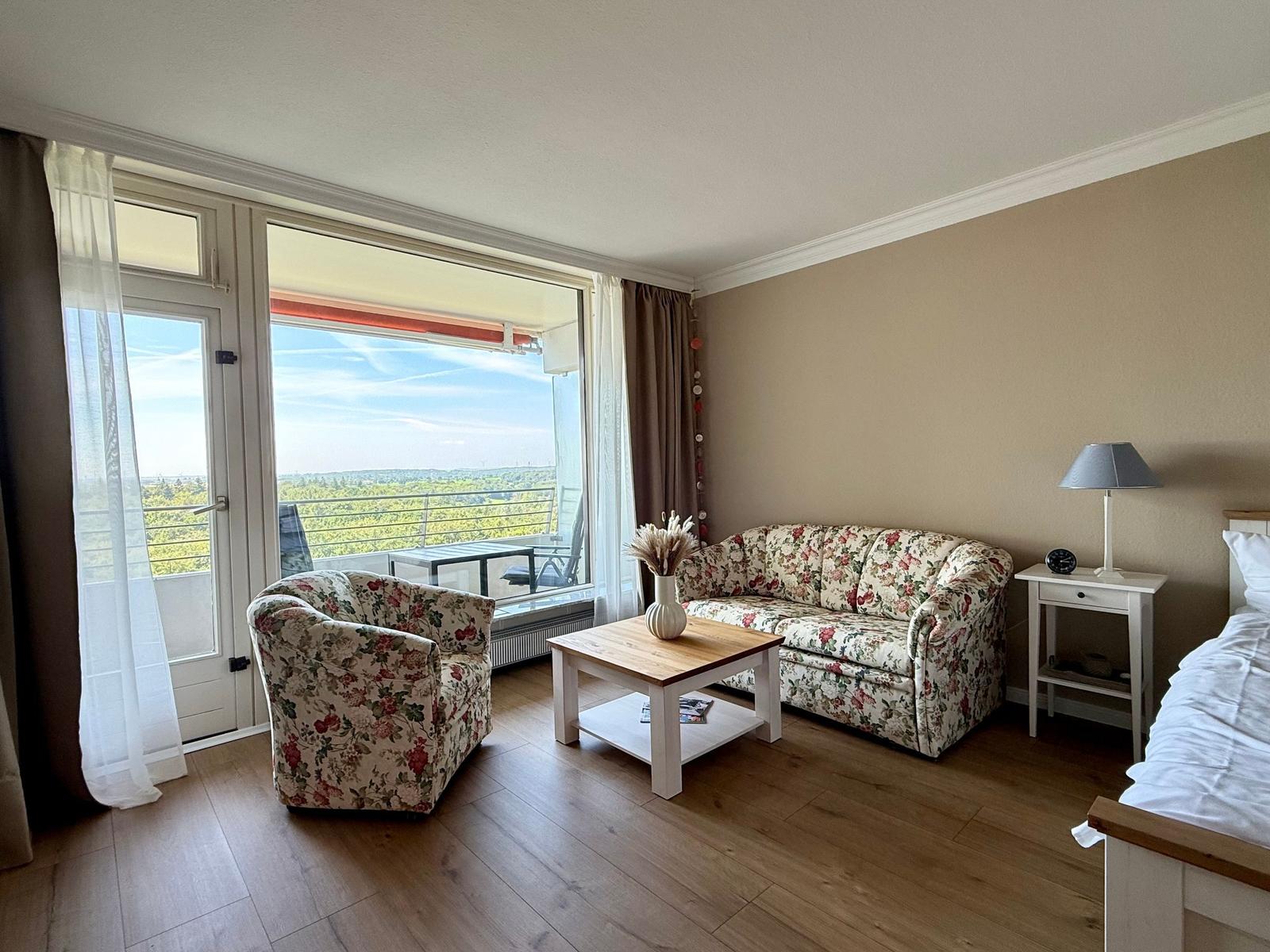 Living room with balcony view. Sofa, armchair, and table.