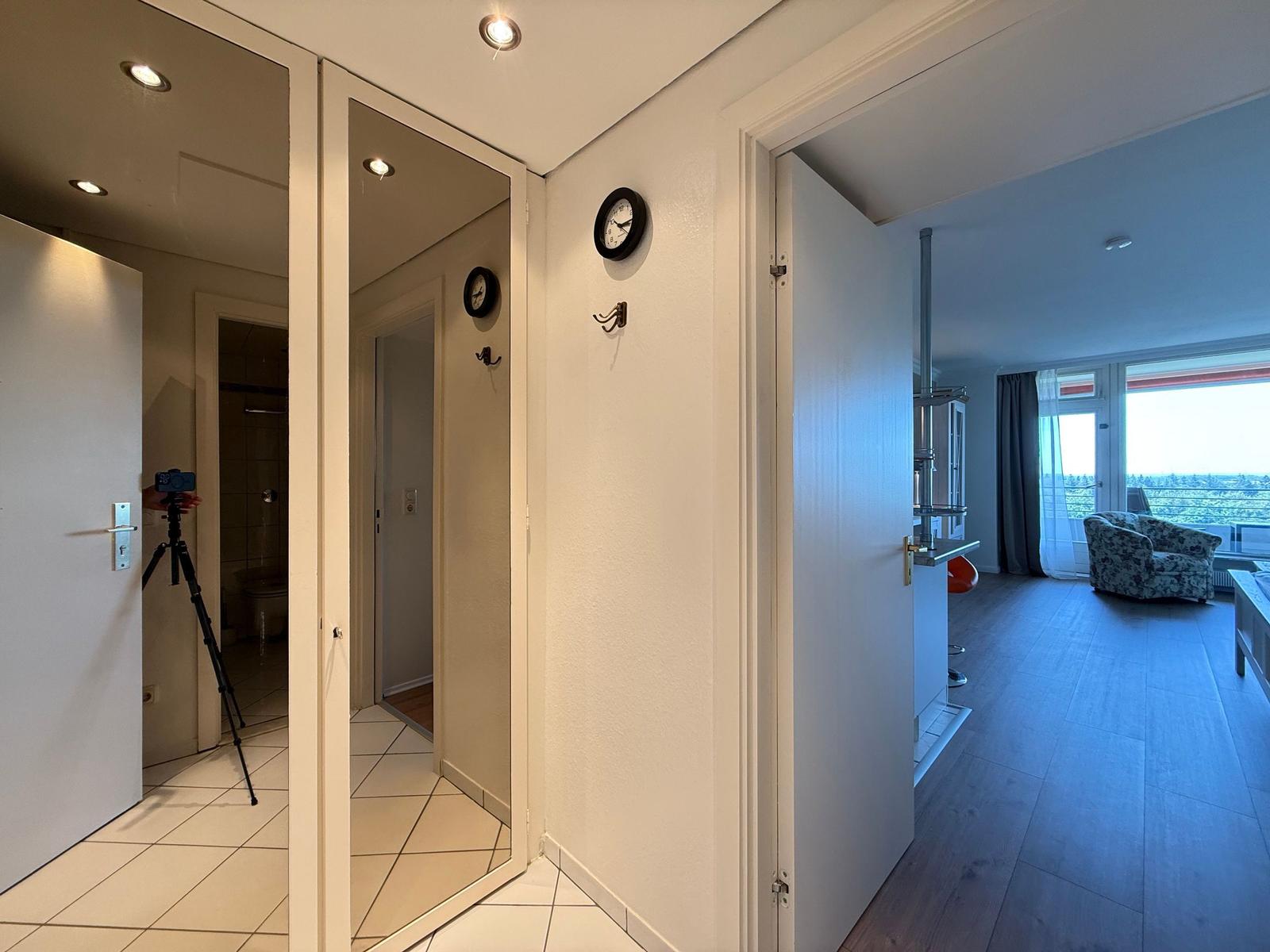 Hallway with view into kitchen and living room with seating and window.
