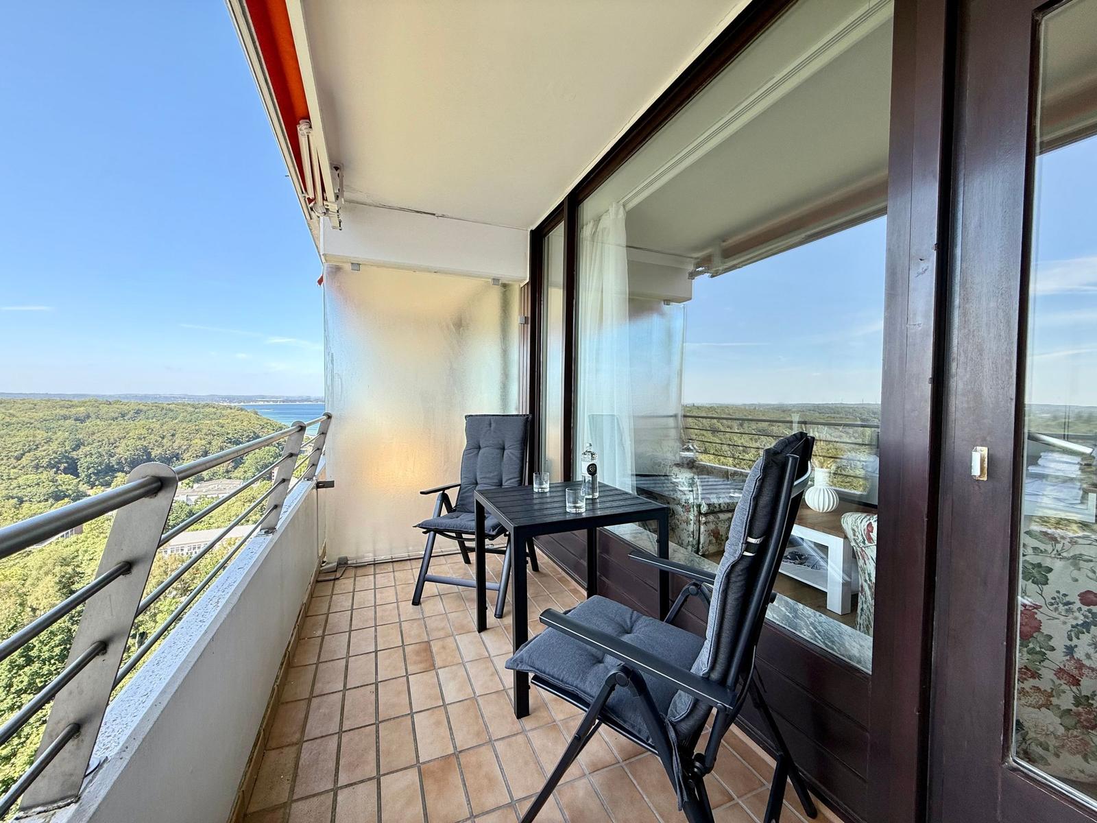 Terrace with table and two chairs. View of forest and lake.