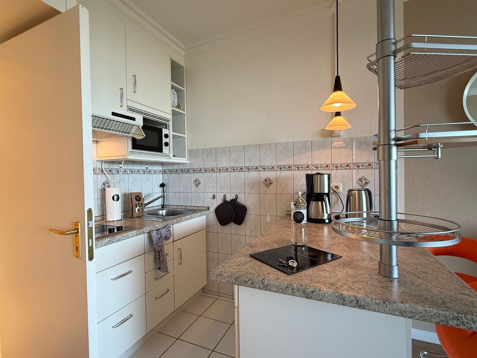 Kitchen with worktop, sink, microwave, and coffee machine.