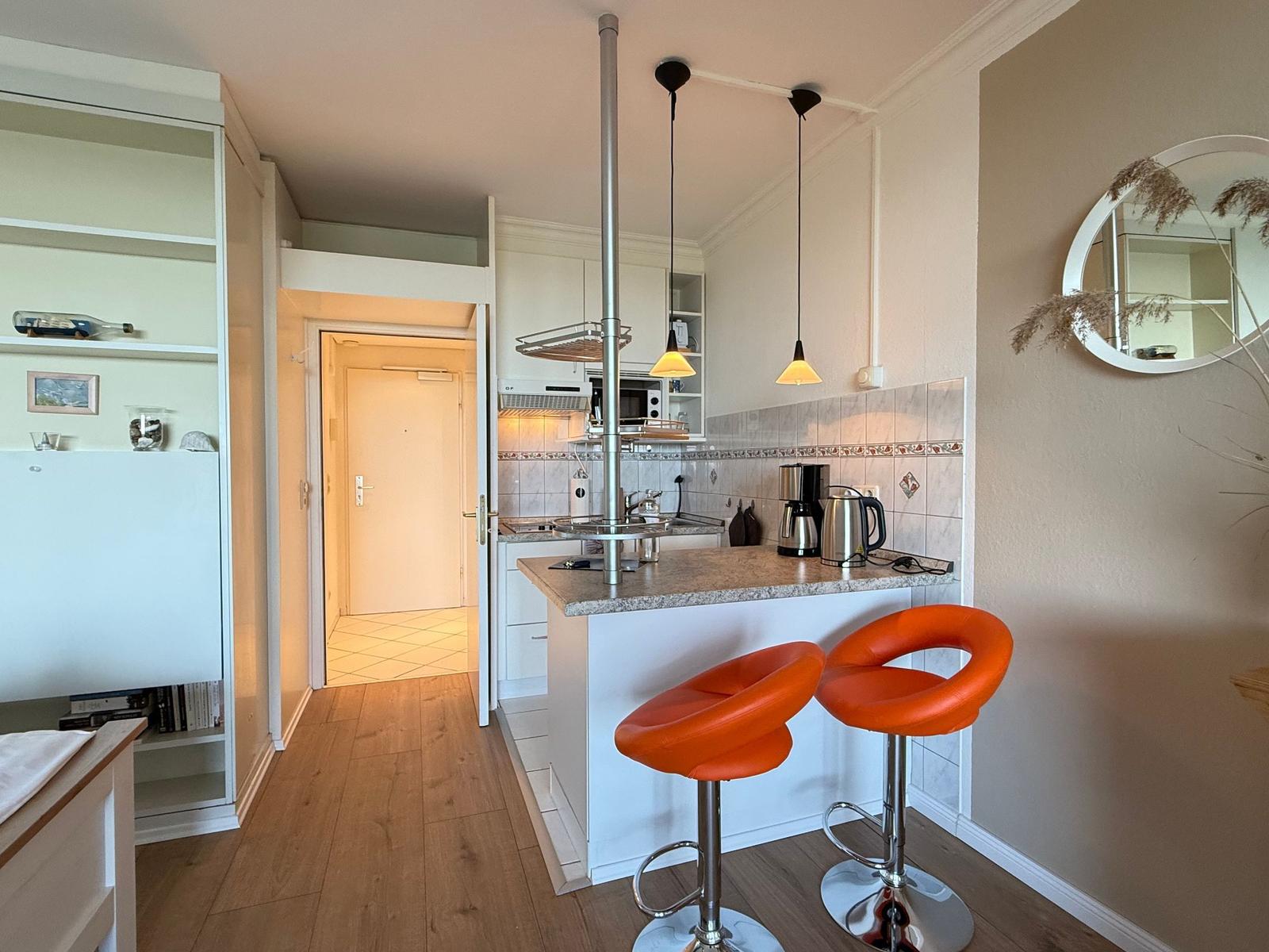 Kitchen with countertop, two orange bar stools, and sink.