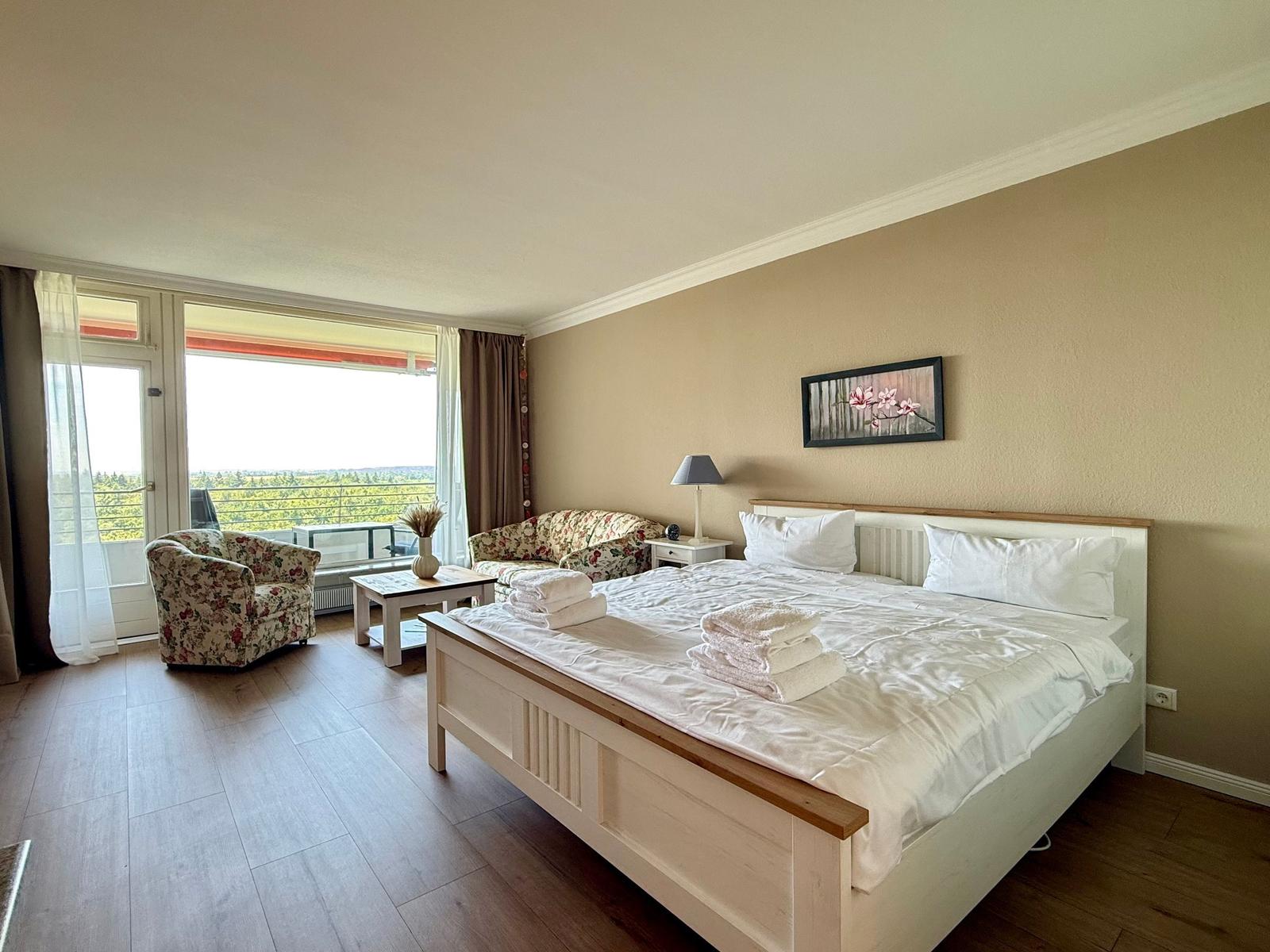 Bedroom with double bed, seating, and balcony view.