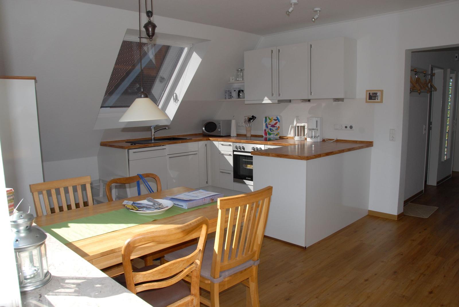 Küche mit Essbereich, Holztisch, Stühle, Dunstabzugshaube und Fenster