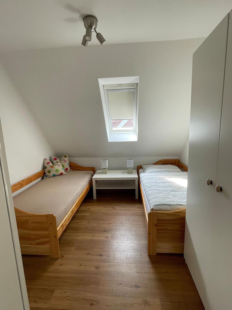 Zimmer mit zwei Betten, Dachschräge, Dachfenster und Holzboden.