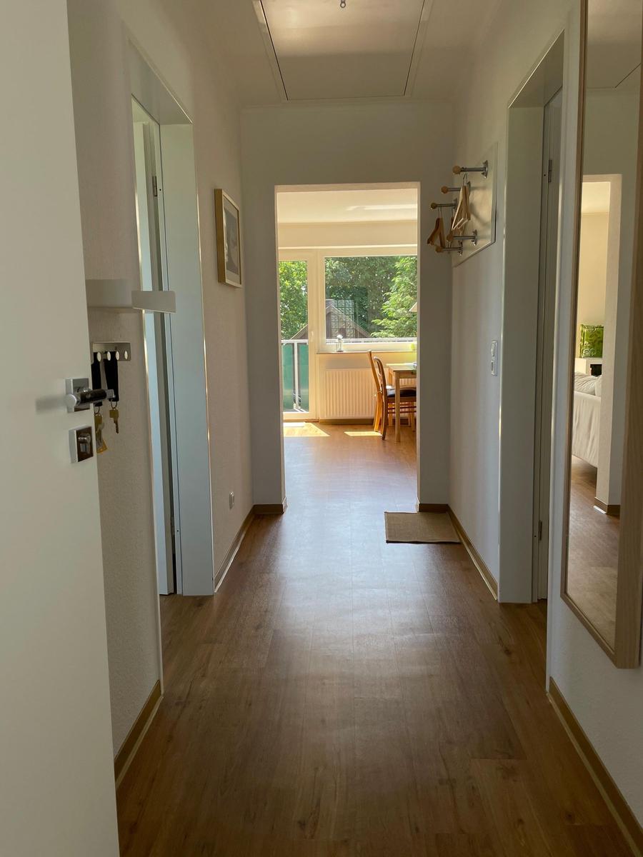 Flur mit Holzboden, Türen zu Wohn- und Schlafzimmer, Blick auf Balkon mit Gartenblick.