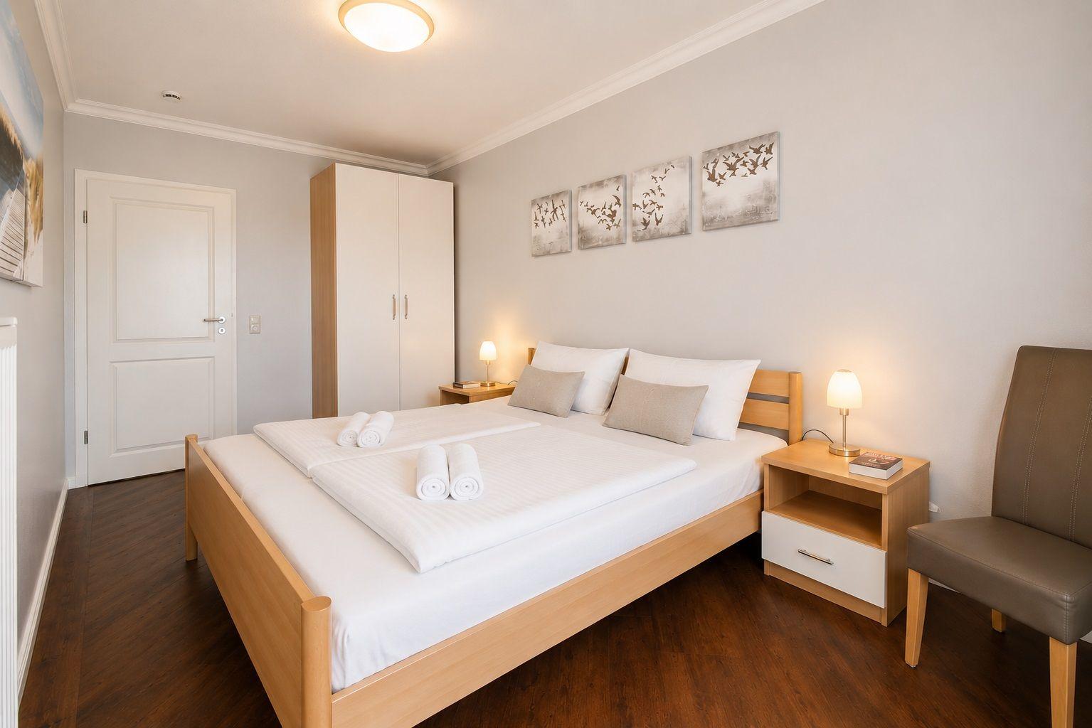 Schlafzimmer mit Doppelbett, Nachttischen, Stuhl und Kleiderschrank.