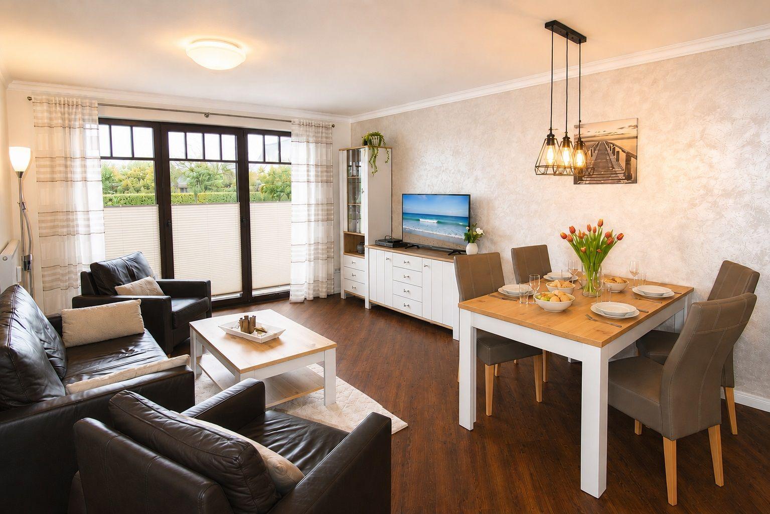 Wohn- und Essbereich mit Sofa, Esstisch und TV. Große Fenster mit Blick auf Garten.