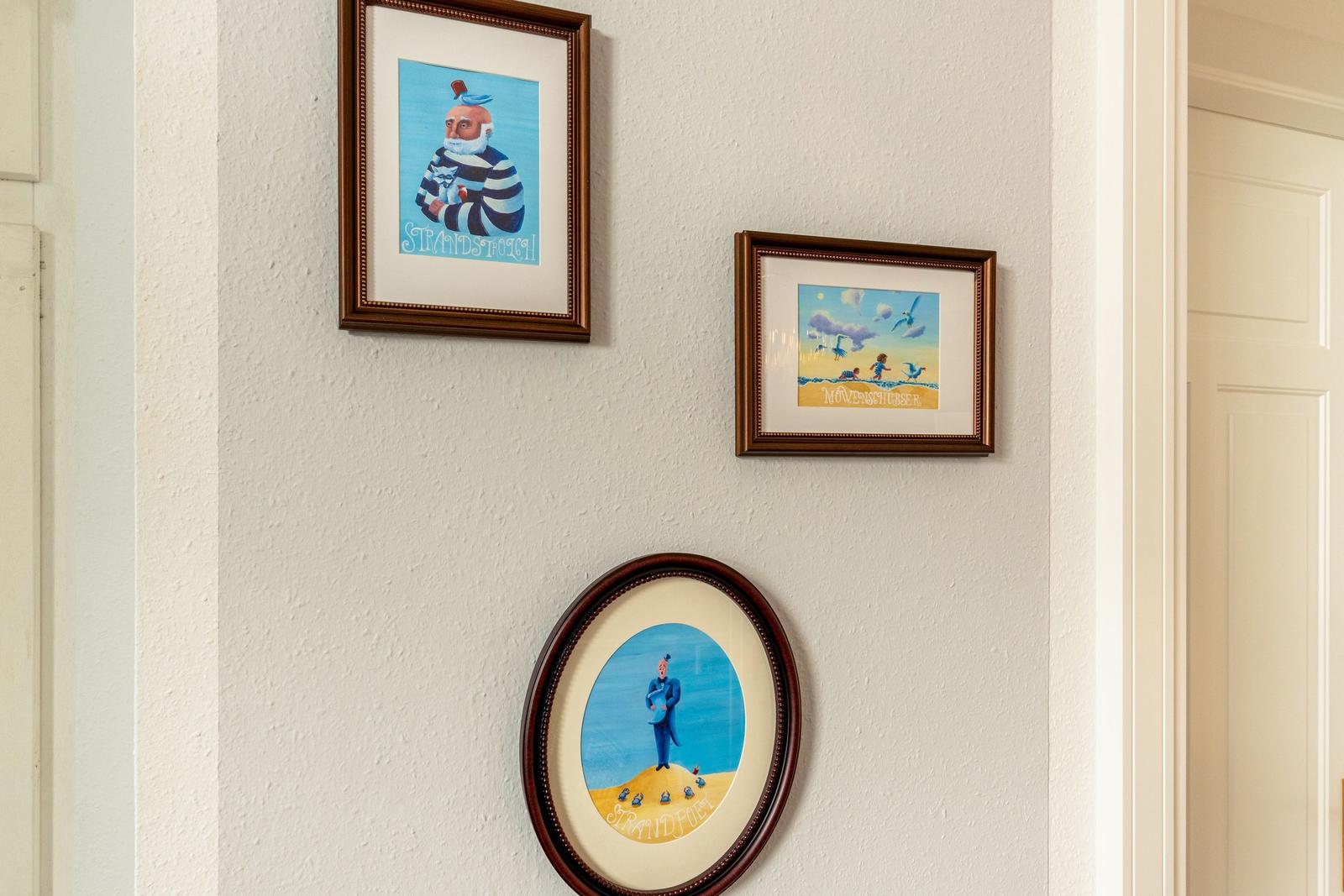 Wall with three framed pictures showing beach motifs.