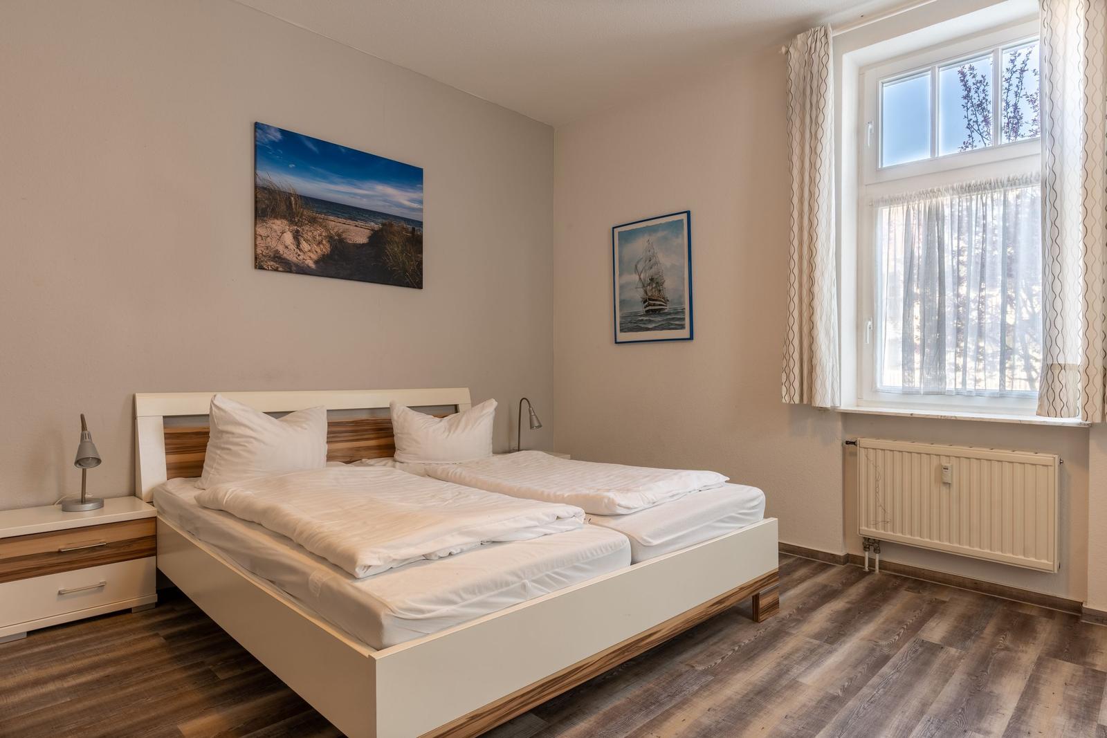 Bedroom with double bed, window, and wall pictures.