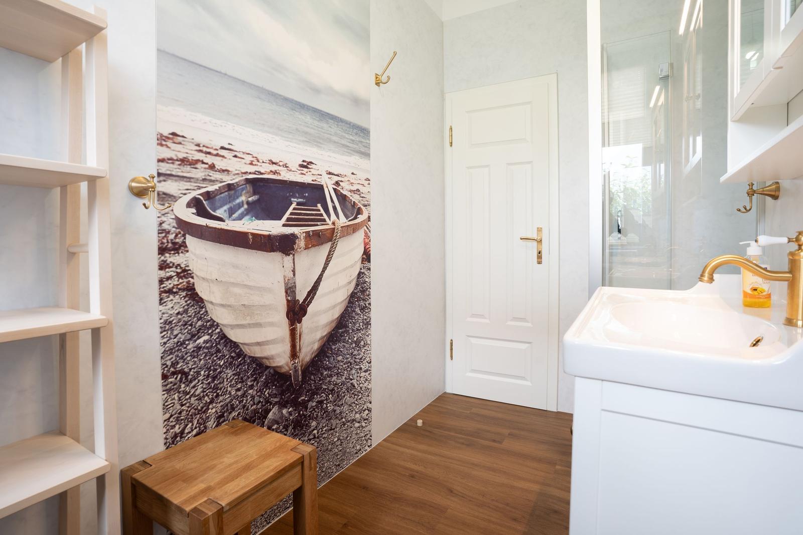 Bathroom with wall mural of a boat, sink, and shower.