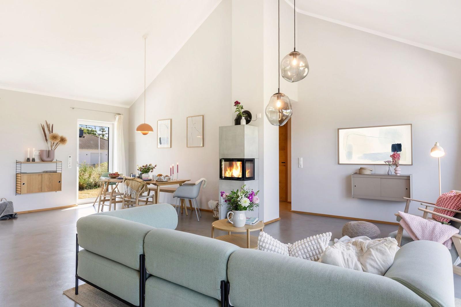 Wohnzimmer mit Sofa, Kamin und Esstisch. Durchgang zur Terrasse.