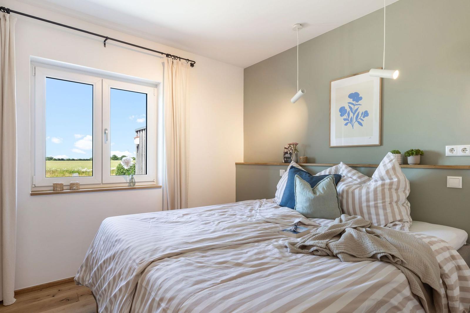 Ein Schlafzimmer mit Bett, Fenster und Wandbild.