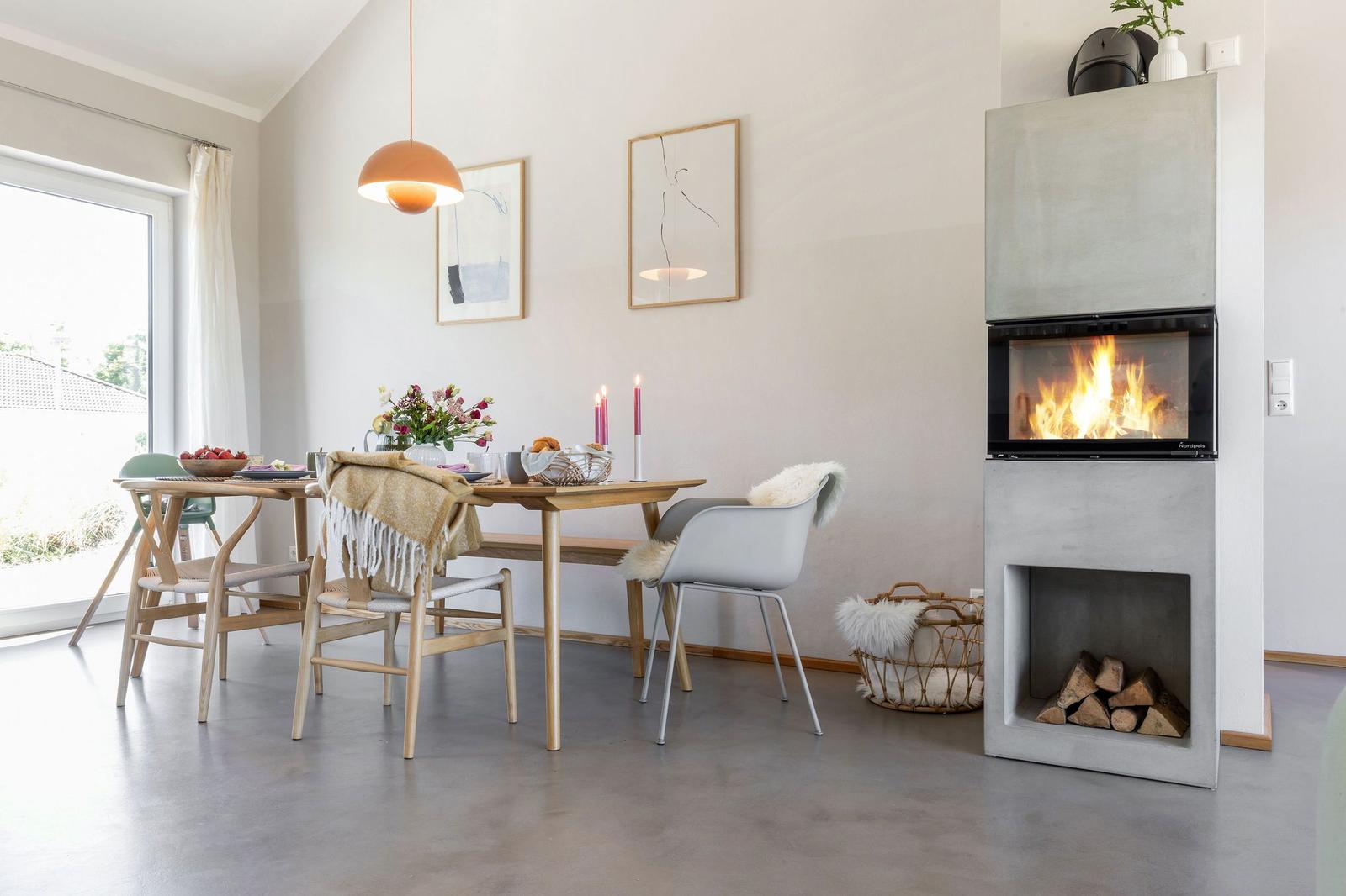 Esstisch mit Stühlen, Kamin und Fenster zur Außenseite.