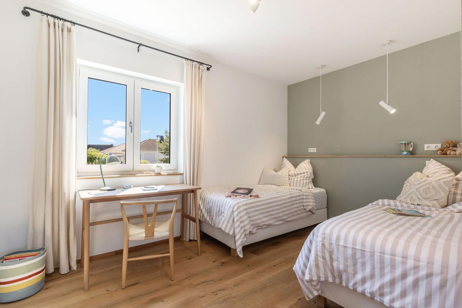 Zwei Betten mit Streifenbetten, Schreibtisch und Fenster mit Blick.