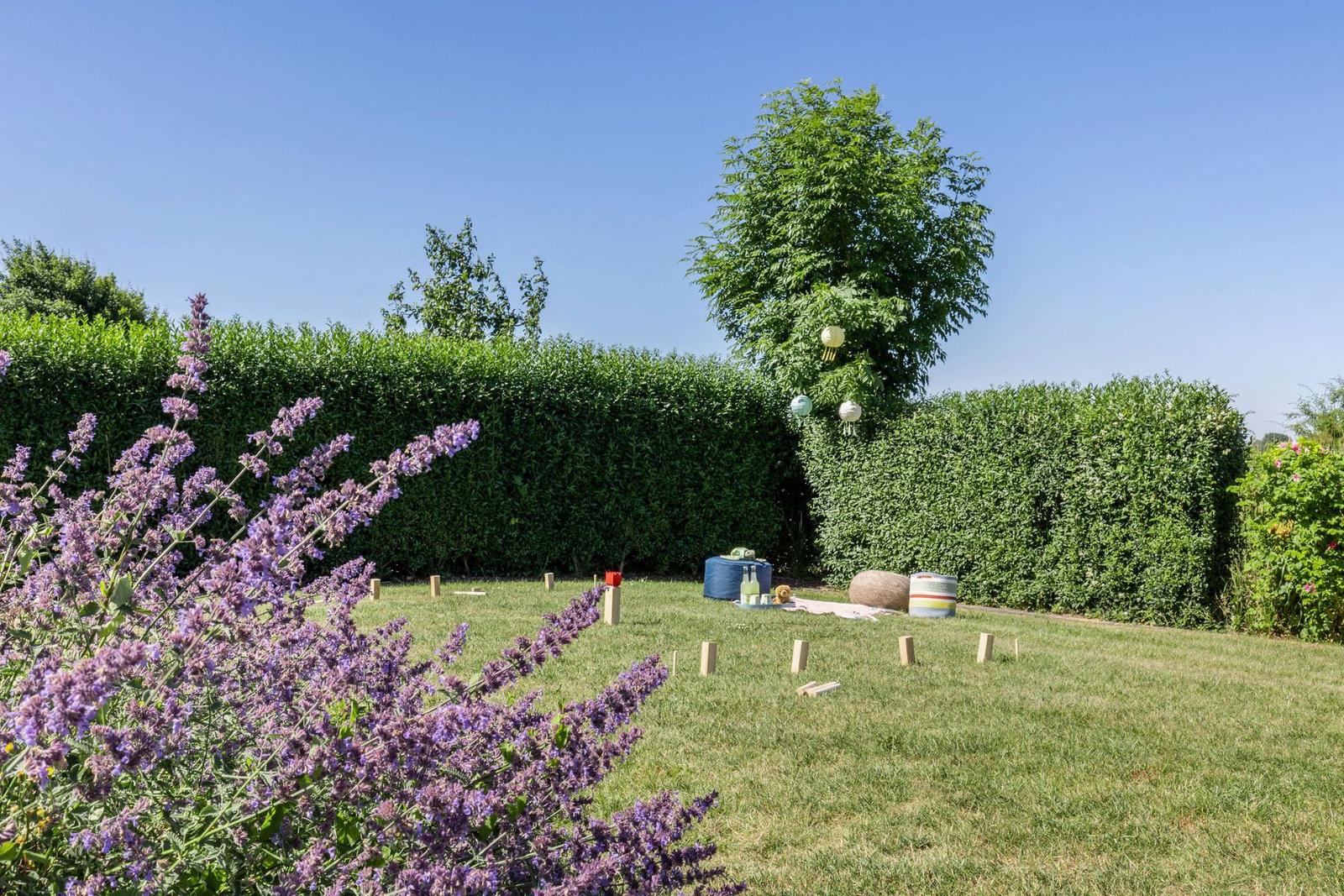 Garten mit Lavendel, Rasenfläche und Bäumen. Spielplatz mit bunten Sitzgelegenheiten.