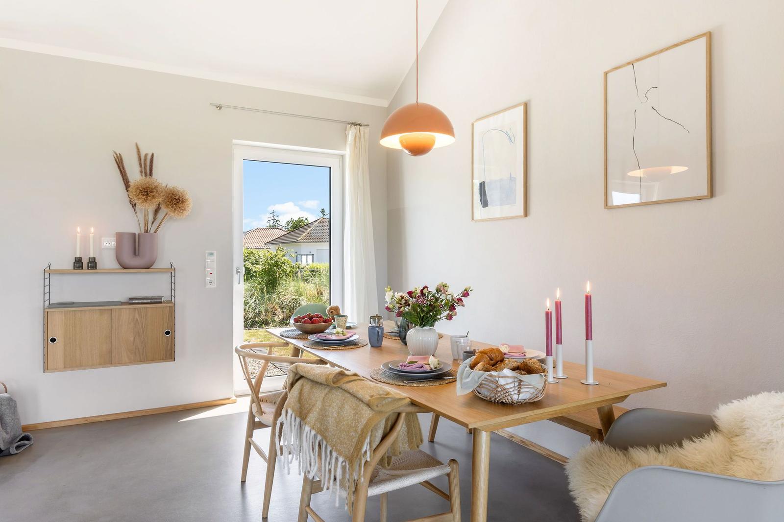 Esszimmer mit Holztisch, Stühlen und Blick auf den Garten.