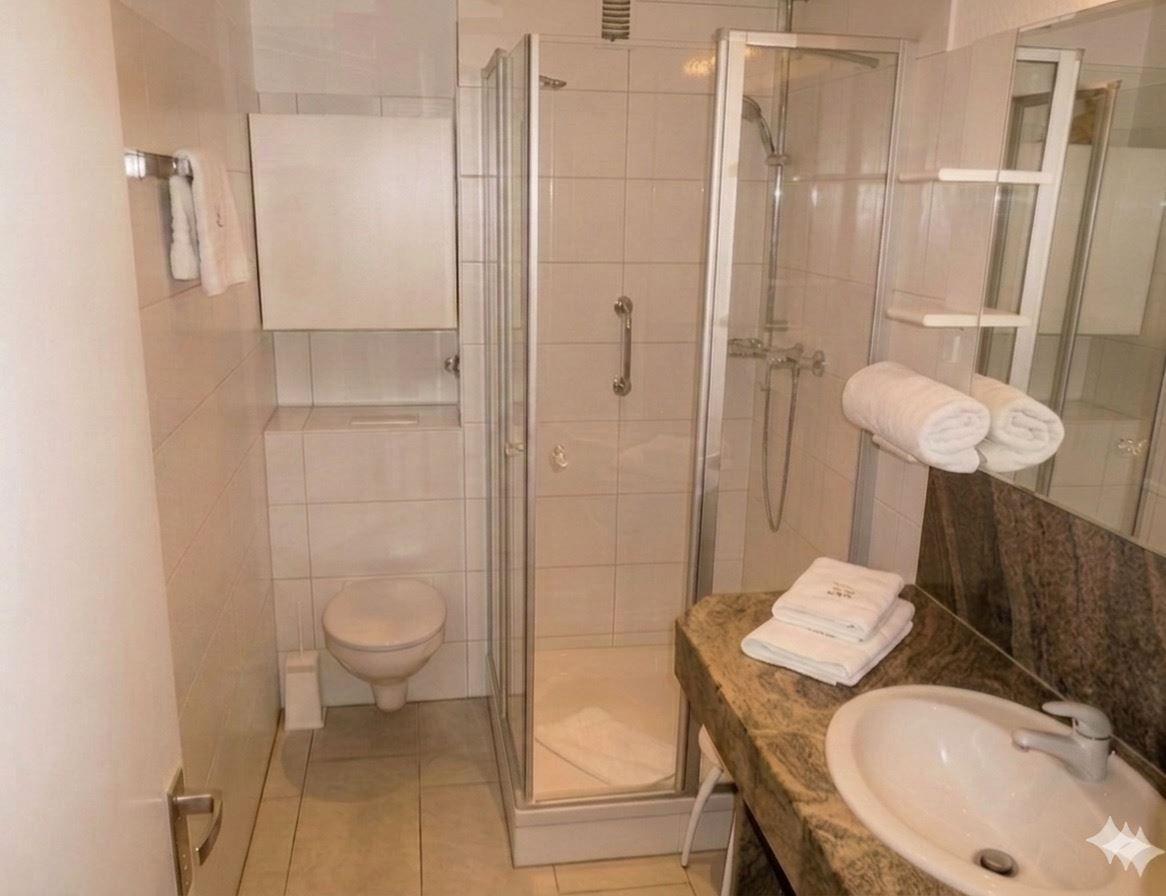 Badezimmer mit Dusche, Toilette und Waschbecken mit Handtüchern.