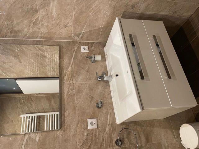 Badezimmer mit Waschbecken, Spiegel und Heizkörper