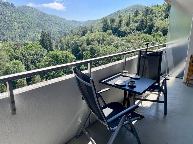 Balcony with table and chairs overlooking forested mountains.