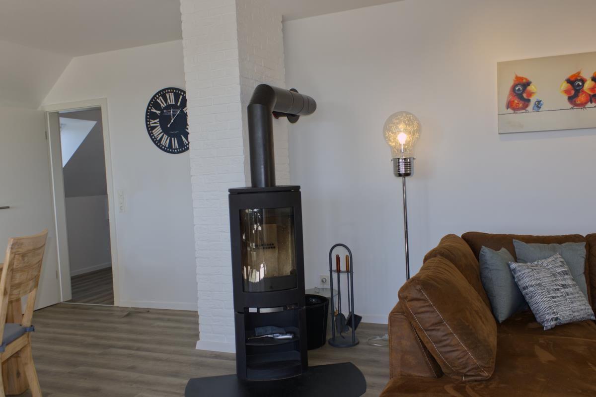 Wohnzimmer mit Kaminofen, Sofa und Wanduhr