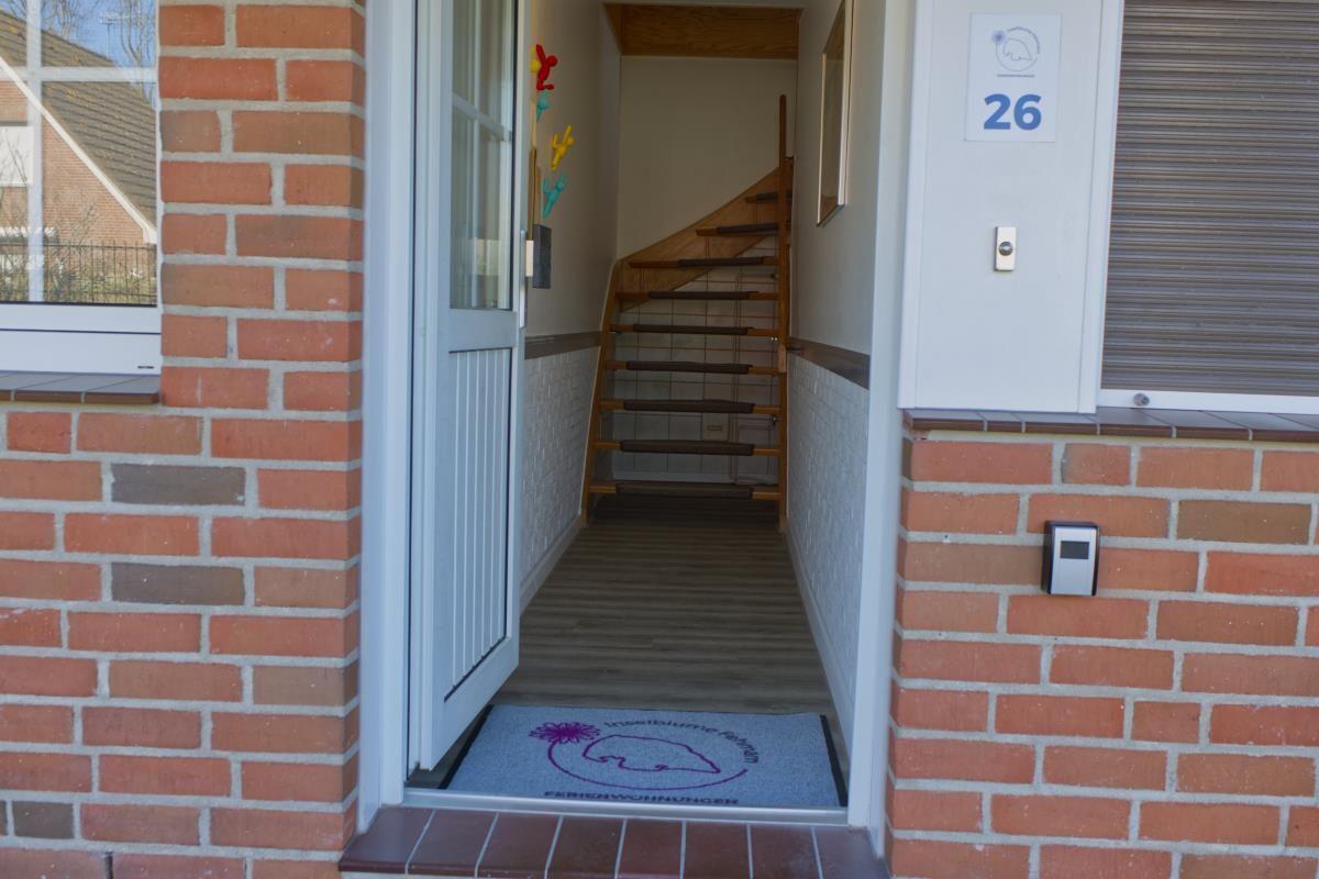 Eingang mit Holztreppe und Tür zum Haus mit Hausnummer 26.