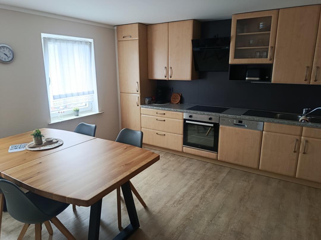 Kitchen with dining area, wooden table, cabinets, and window.