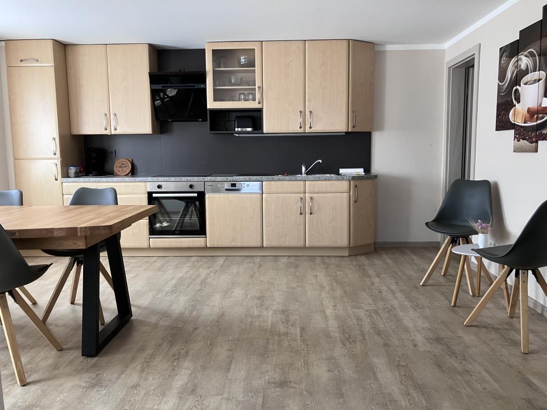 Kitchen with laminate cabinets, stainless steel appliances, and dining table with chairs.