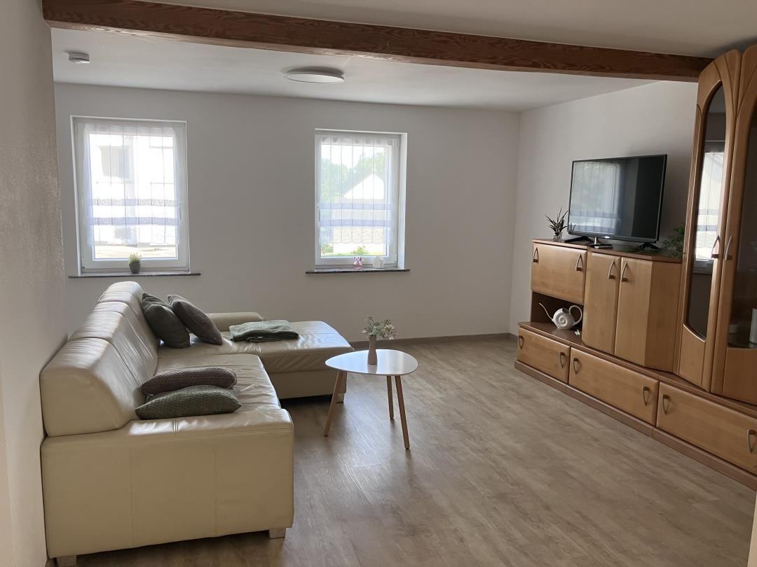 Living room with sofa, TV, and wooden furniture.
