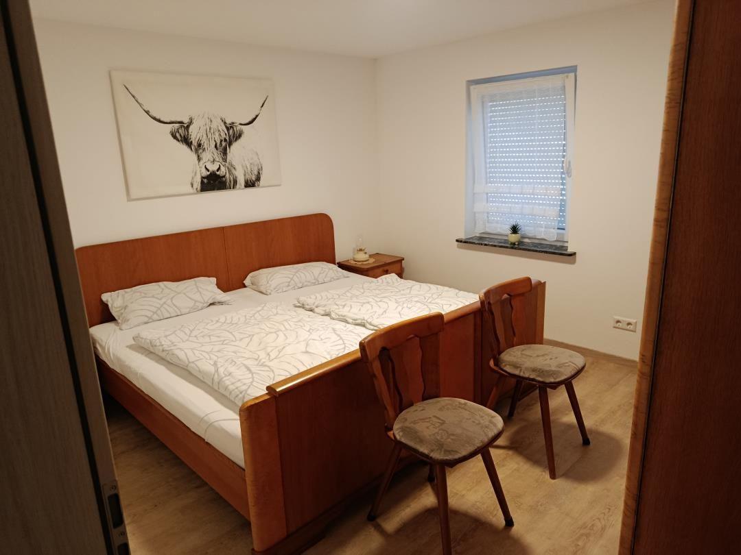 Bedroom with double bed, two chairs, and wall art of a Highland cow.