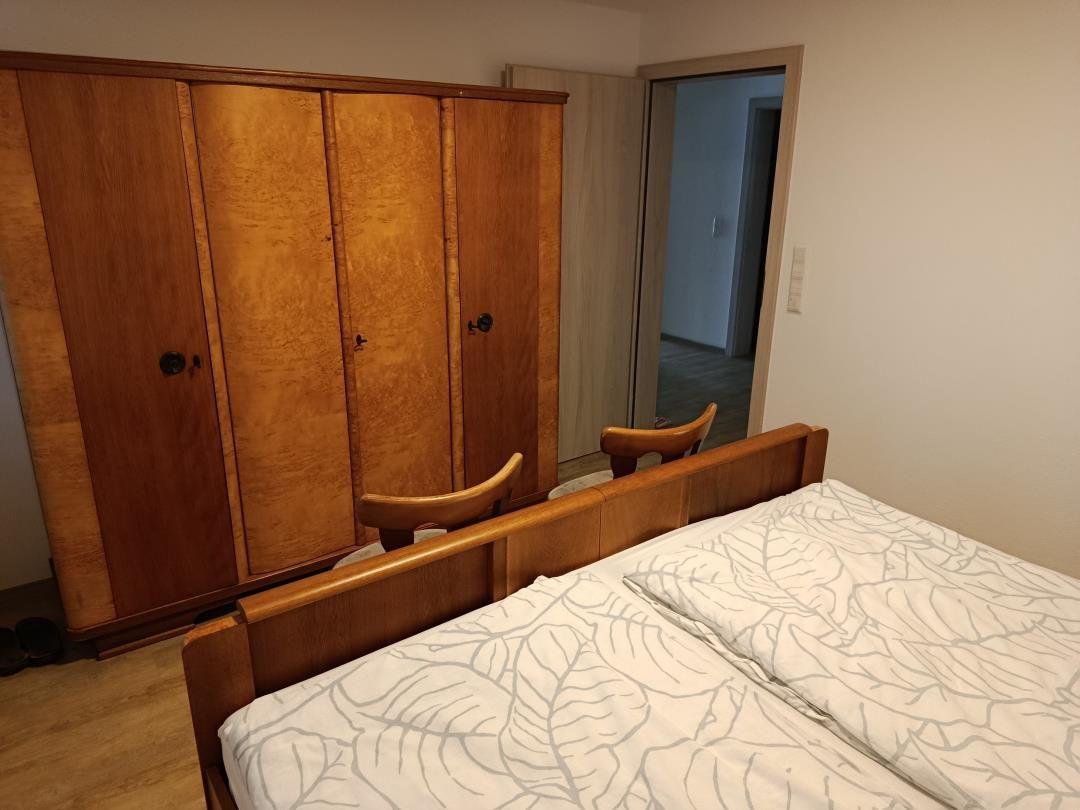 Bedroom with wooden bed and wardrobe. Passage to another room.