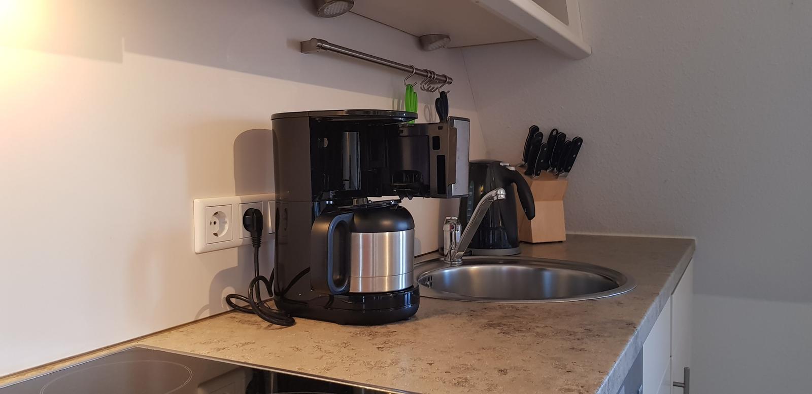 Küchenzeile mit Kaffeemaschine, Spüle und Messerblock.
