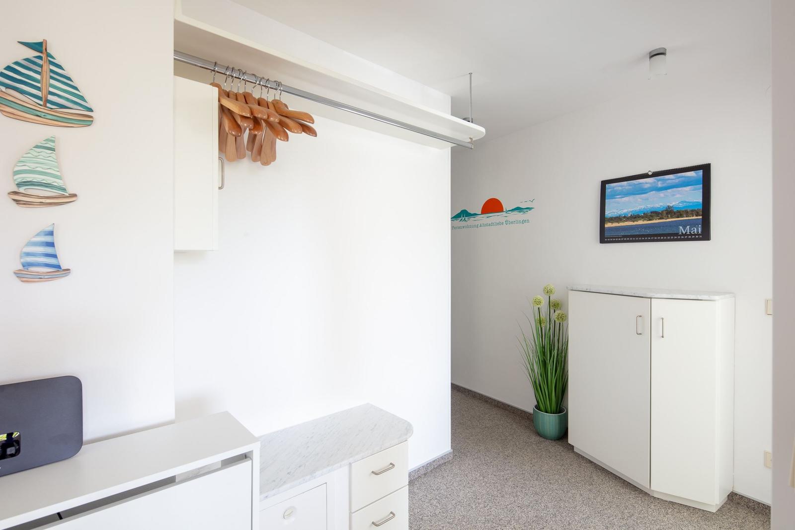 Wohnraum mit Kleiderschrank, Pflanze und Wanddekoration. Kalender an der Wand.