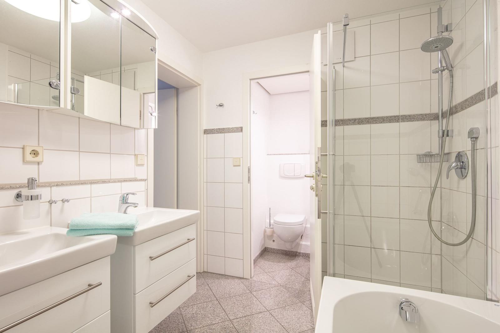 Badezimmer mit Dusche, Badewanne, Waschbecken und Toilette
