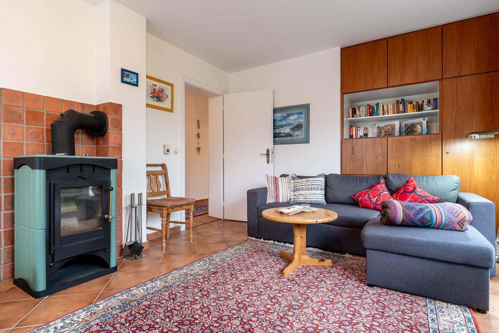 Wohnzimmer mit Sofa, Holztisch, Kamin und Bücherregal.