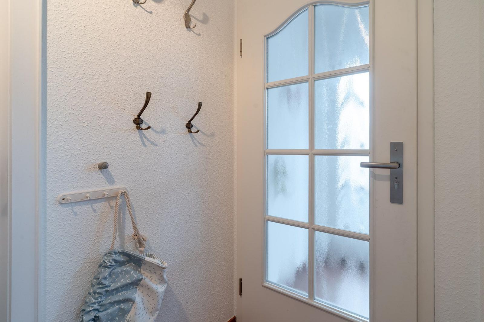 Eingangsbereich mit Garderobe und Tür mit getöntem Glas.