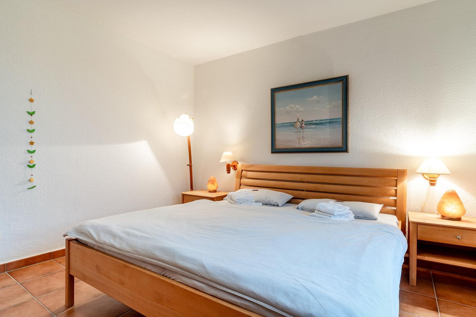 Ein Schlafzimmer mit Holzbett, zwei Nachttischen und Wandbild.