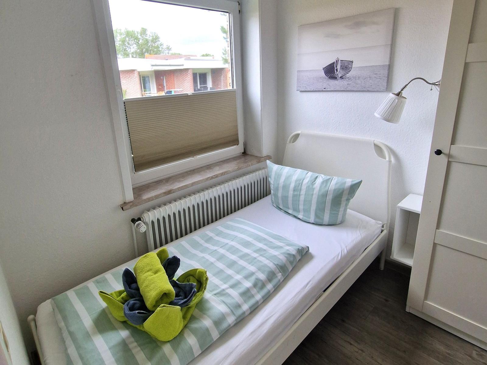 Ein Schlafzimmer mit Bett, Fenster und Wandbild.