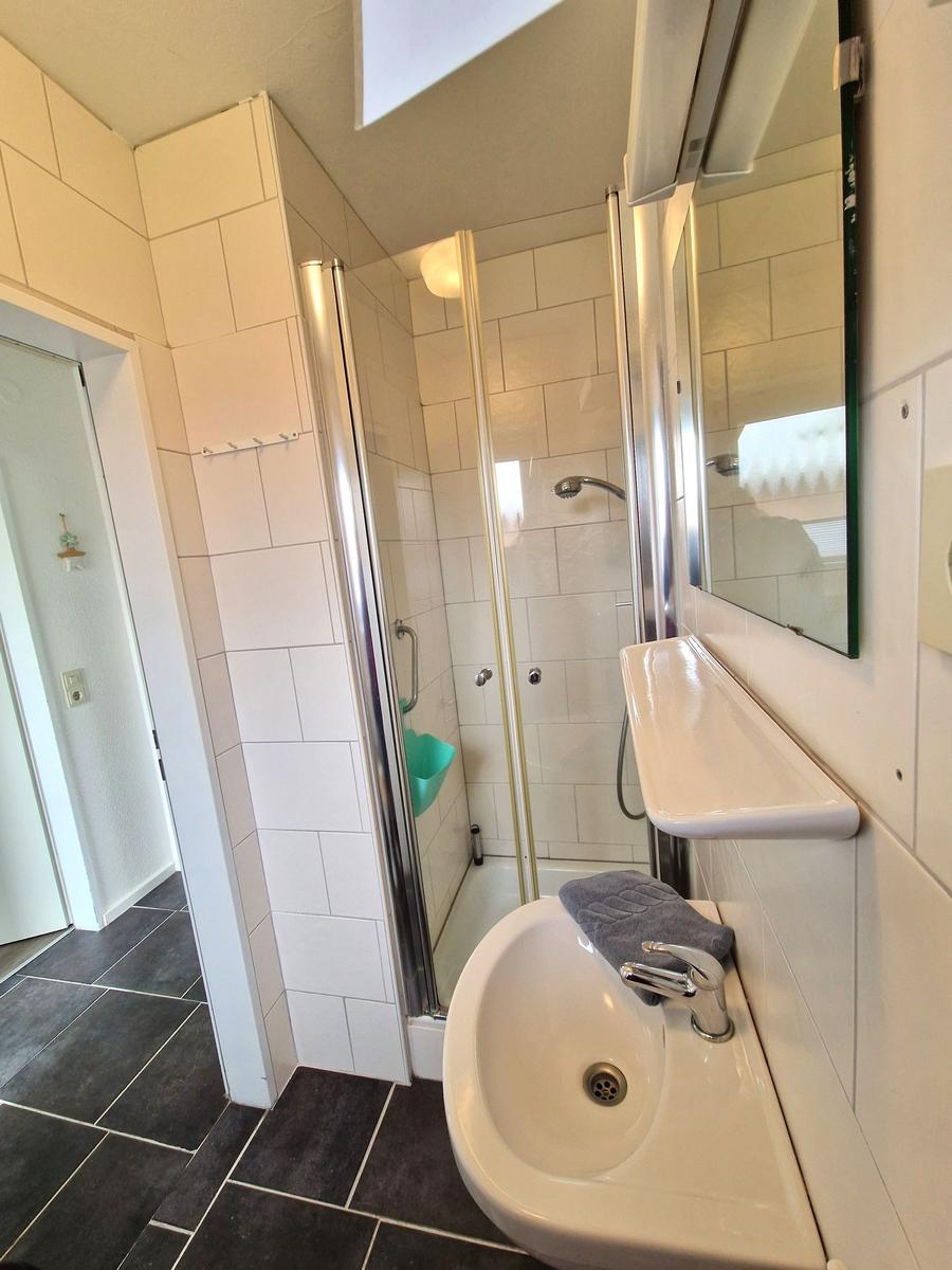 Badezimmer mit Dusche, Waschbecken und Spiegel