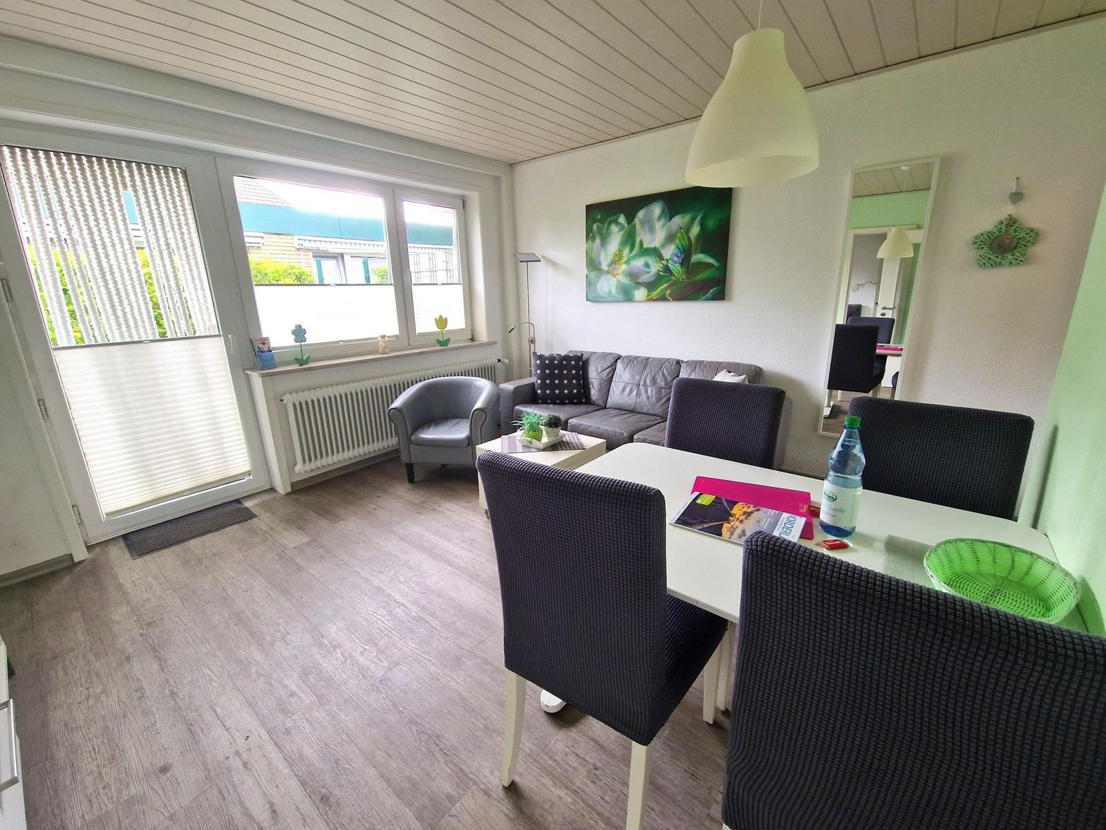 Wohn- und Essbereich mit Sofa, Stühlen und Fenster. Decke mit Holzverkleidung.
