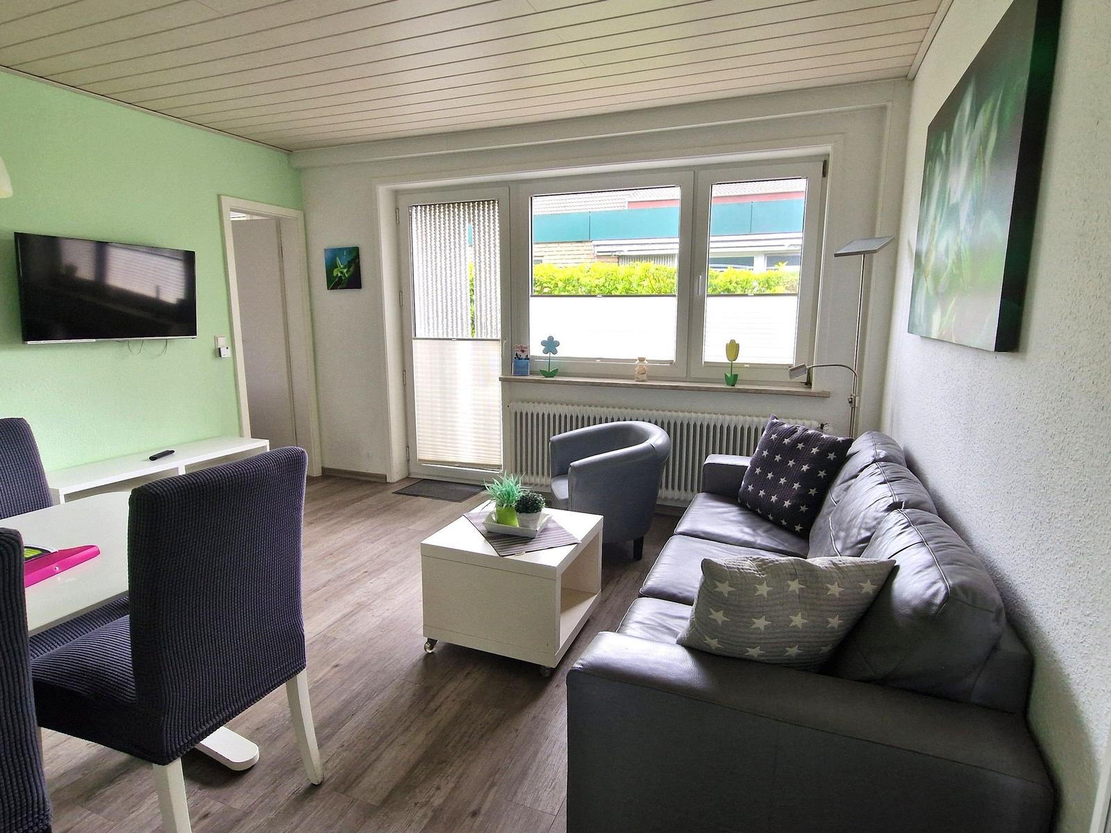 Wohnzimmer mit Sofa, Sitzgelegenheit und Fernseher an der Wand.