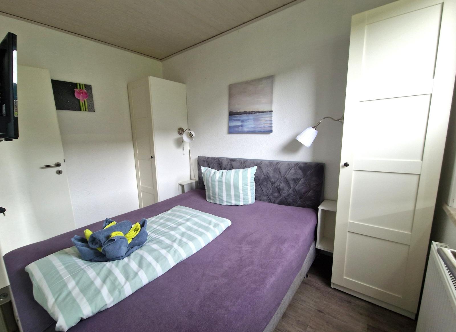 Schlafzimmer mit Bett, Kleiderschrank und Wandbild.
