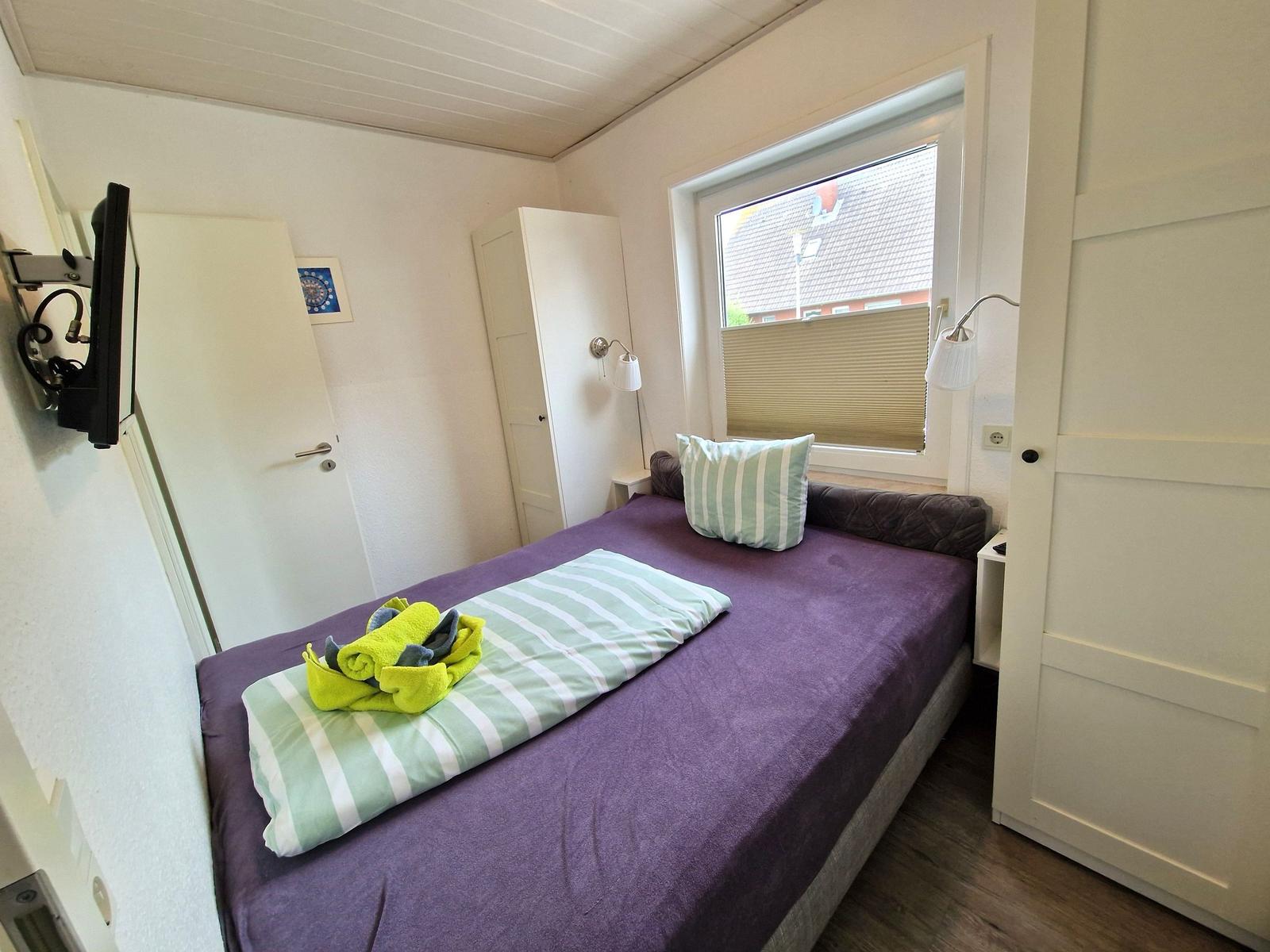 Schlafzimmer mit Bett, Fenster und Wand-TV