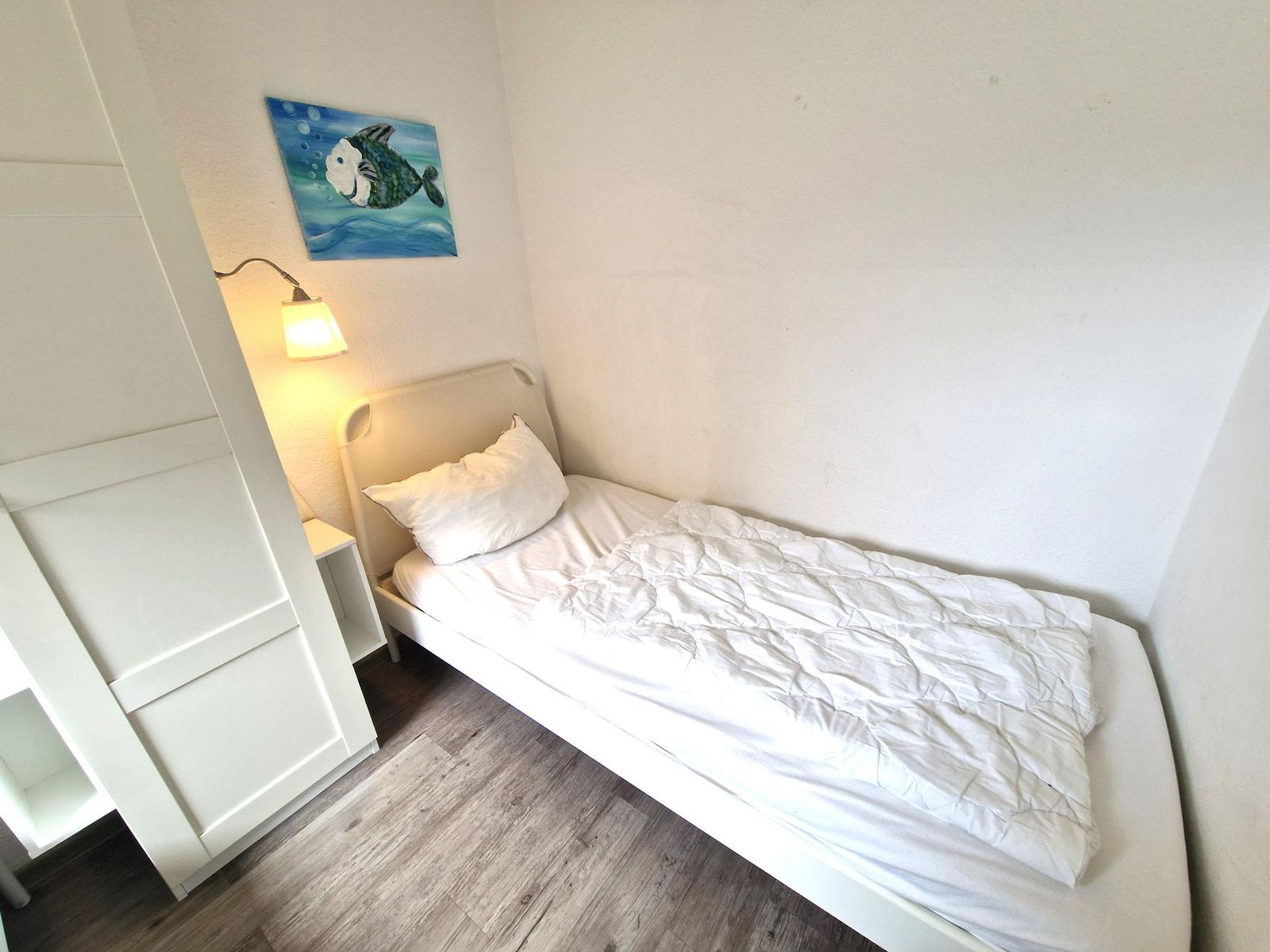 Ein Schlafzimmer mit einem Bett, einer Wandlampe und einem Wandbild.
