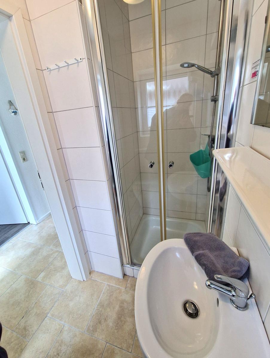 Badezimmer mit Dusche, Waschbecken und Handtuch.