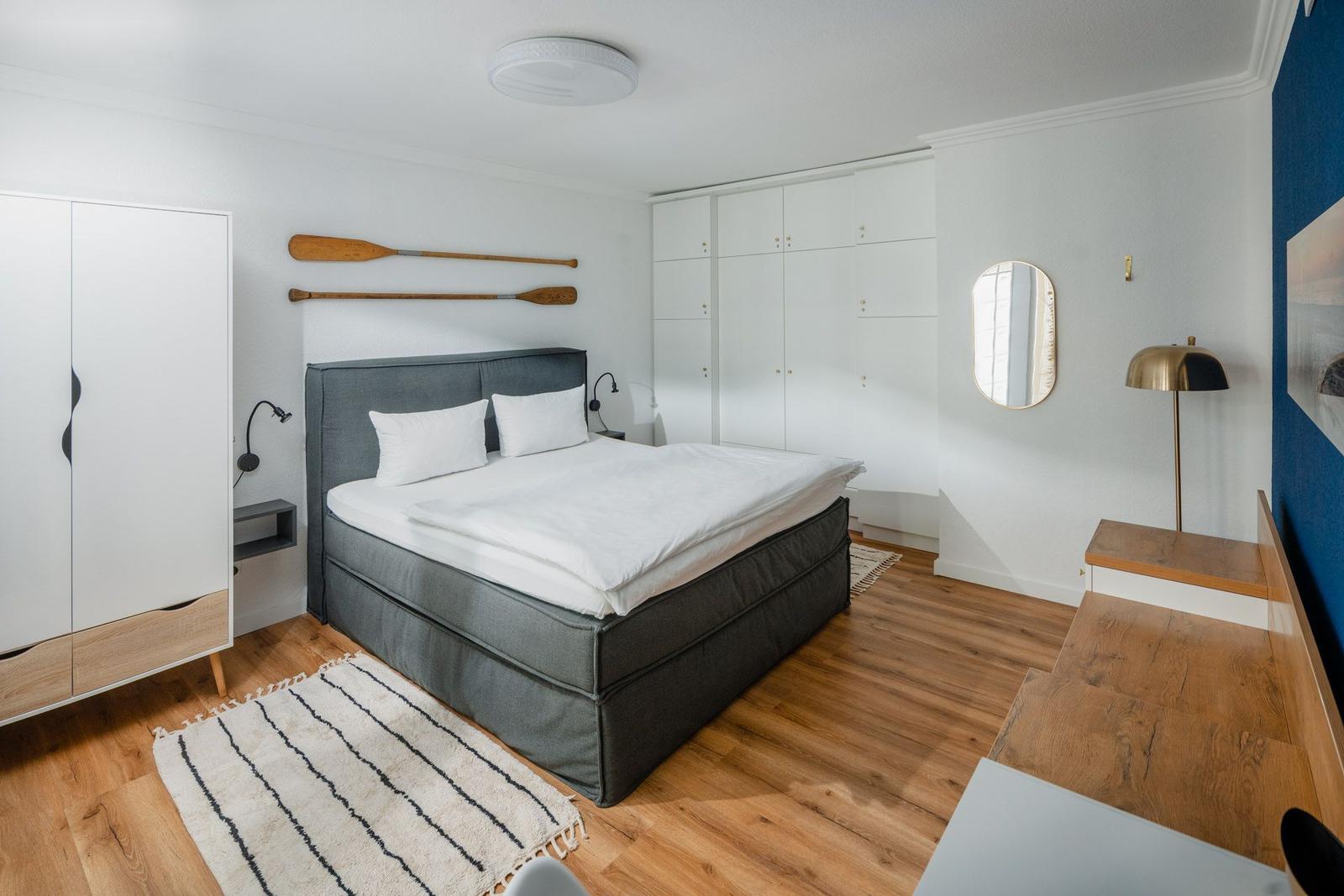 Schlafzimmer mit Doppelbett, Schrank und Holzboden.