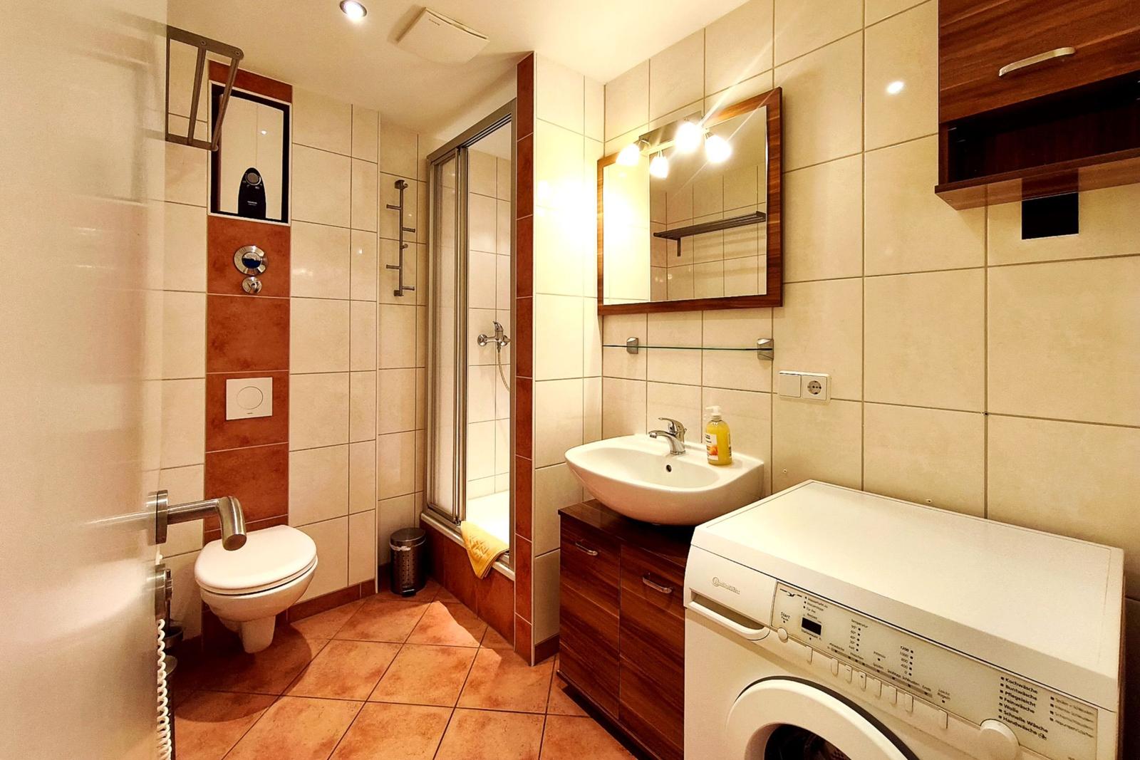 Gepflegtes Badezimmer mit Dusche, Waschbecken und Waschmaschine
