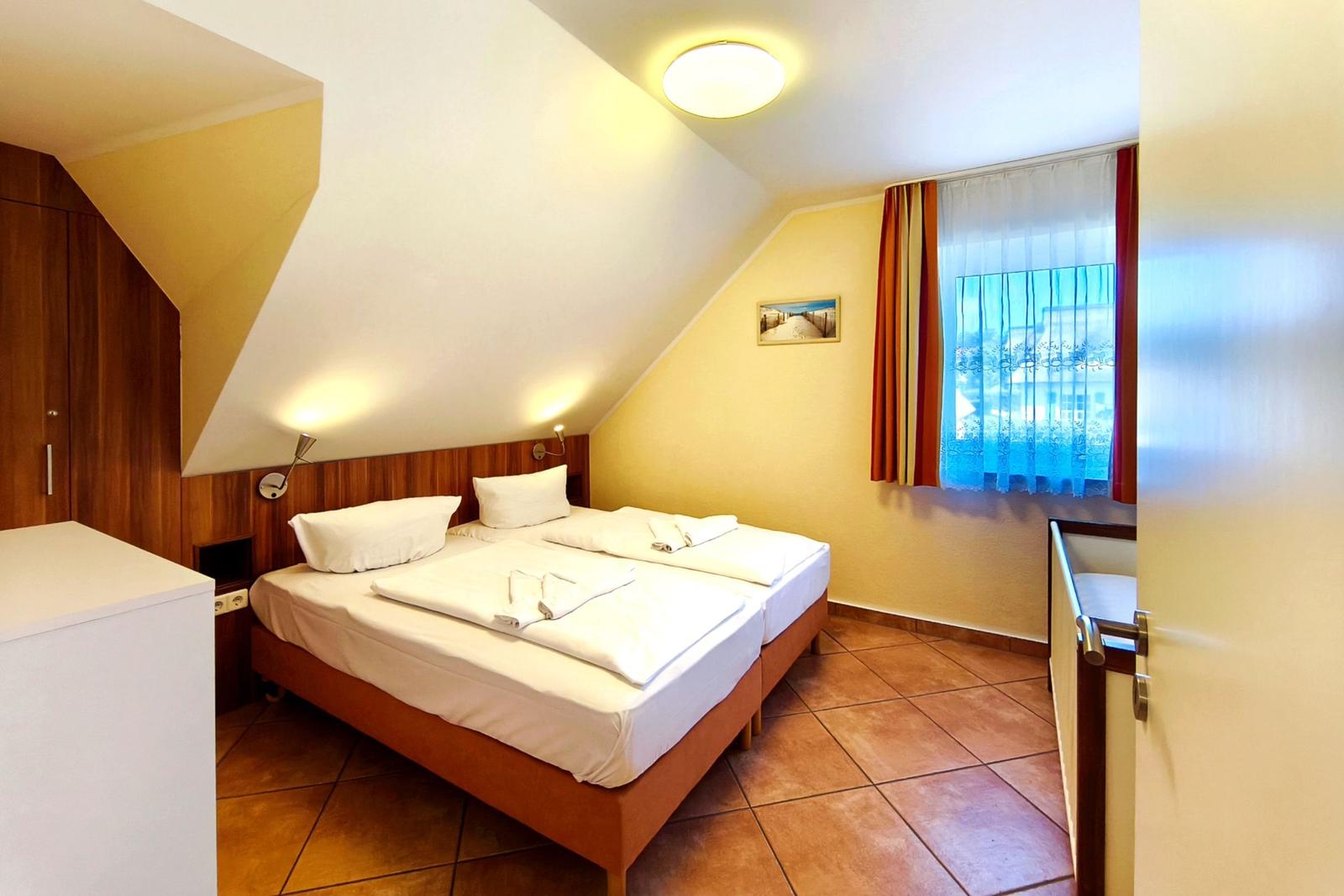 Behagliches Schlafzimmer mit großem Doppelbett unter behaglicher Dachschräge
