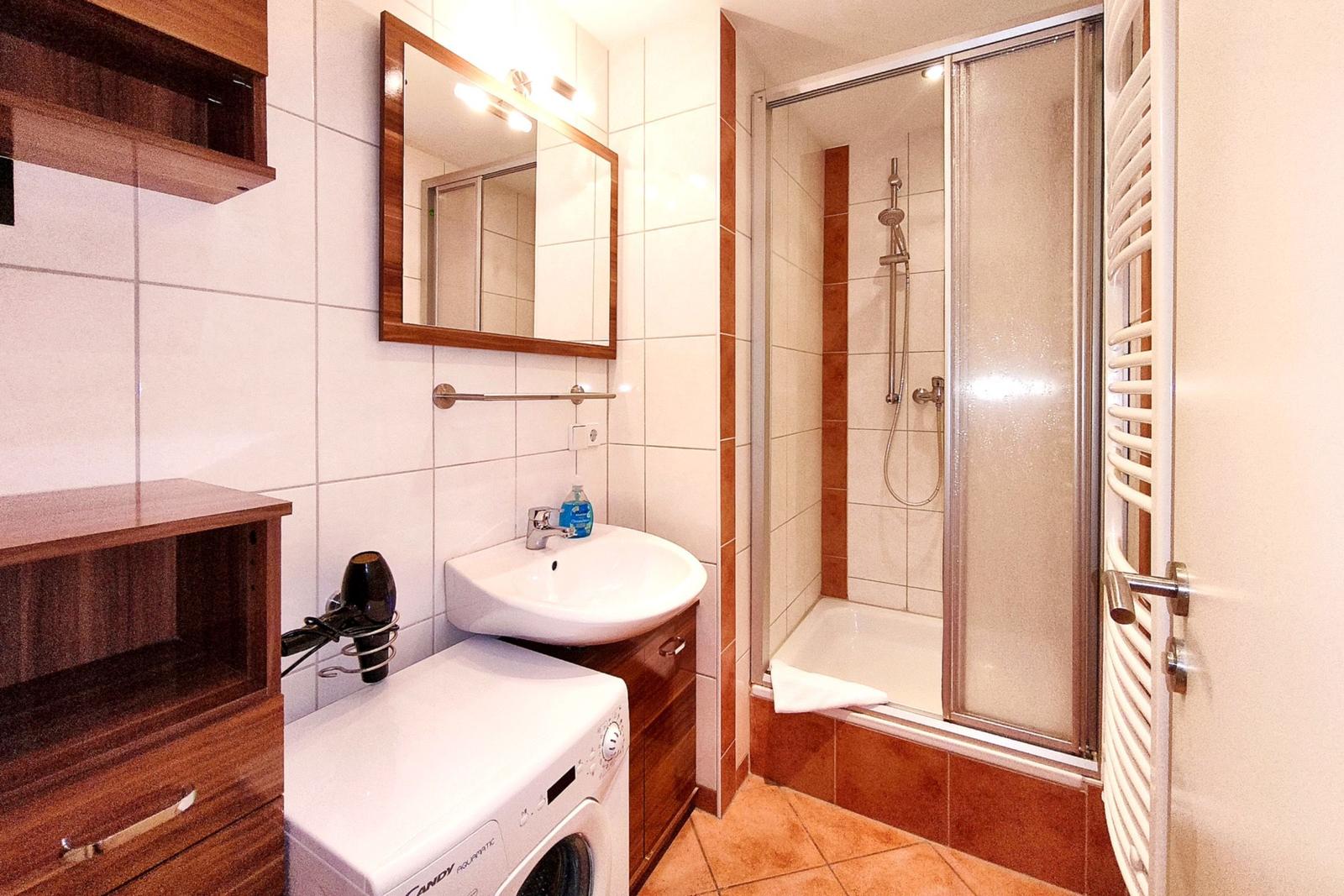 Modernes Badezimmer mit Glasedelstahl-Dusche und Waschmaschine